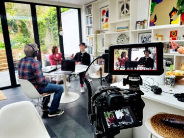 A BTS photo of Dom Salmon's Z 6II camera set up with his cage. For the Nikon magazine. Caption can read: Here Dom (check shirt) is recording a podcast with Kerry from wellness consultancy, Together We Breathe and Matt from experimental organisers. Realm at the London shoot location Sourcey)  and is using his Z6ii in tandem with the very popular Atomos Ninja V to record the Pod for YouTube. The Ninja is great for cheap, high volume storage recording and a big bright monitor, one less thing thing to worry about! Shot is taken by an Iphone to show the use of a cage